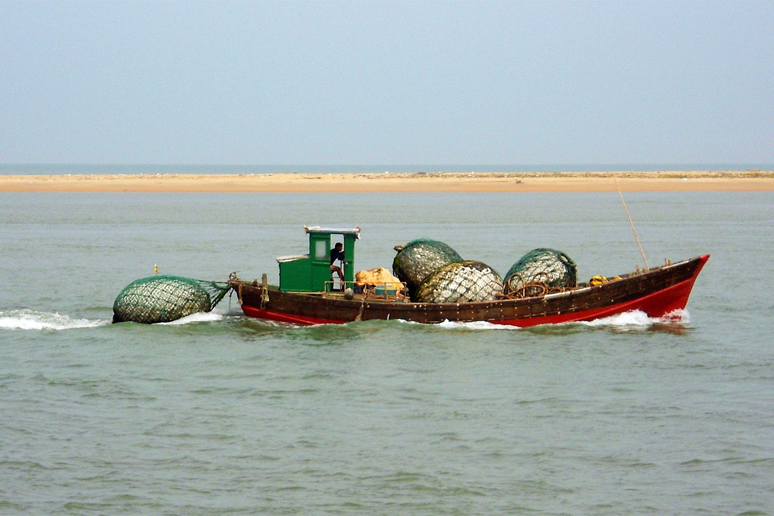 A boat tows balls of salvaged polystyrene in fishnets off Xinbu Island, on the north coast of Hainan Province, China.