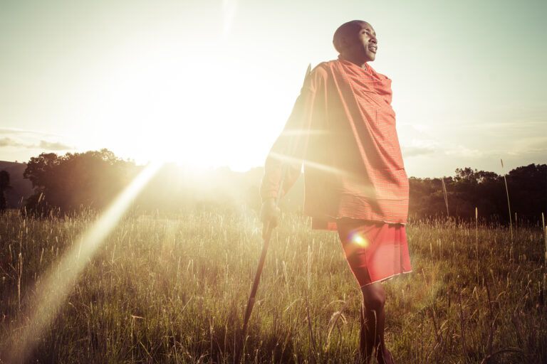 A Maasai man armed with a spear stands on a hilltop close to the highest point of the Loita hills.