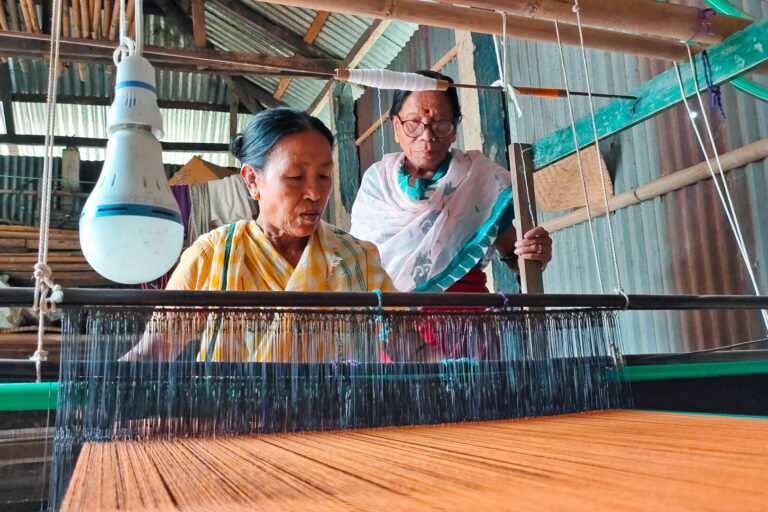 Radhavato Devi training an Indigenous woman to make sari with banana fiber.