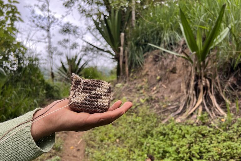 Silvia Vetancourt holds out a coin purse she is crocheting from cabuya fiber on the path to Plaza Gutierrez, Ecuador. Photo by Liz Kimbrough.