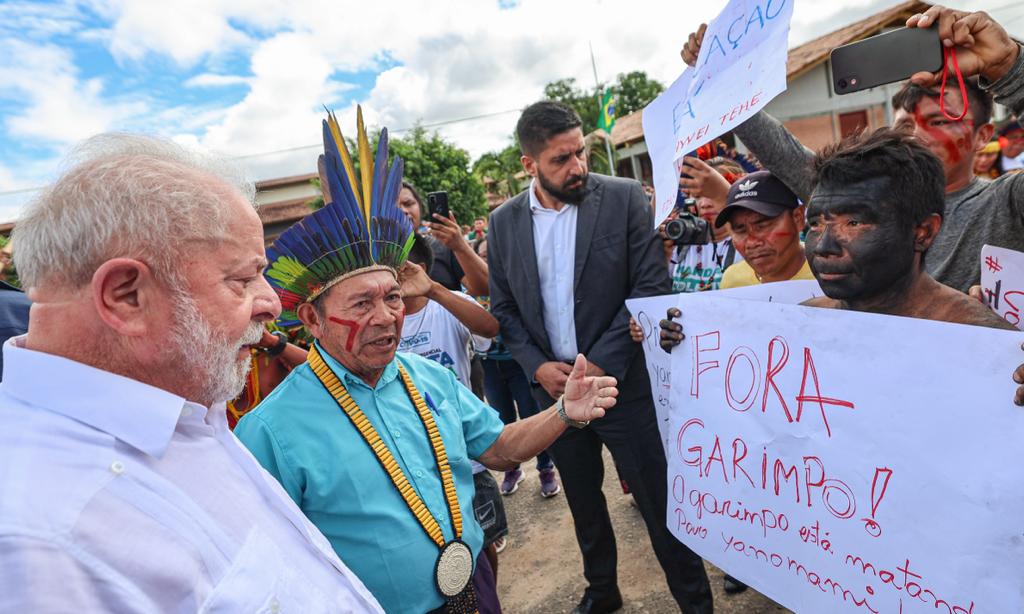 A Yanomami person holds a sign saying “Get Out Miners. Mining is killing the Yanomami people” during President Luiz Inácio Lula da Silva’s recent visit.