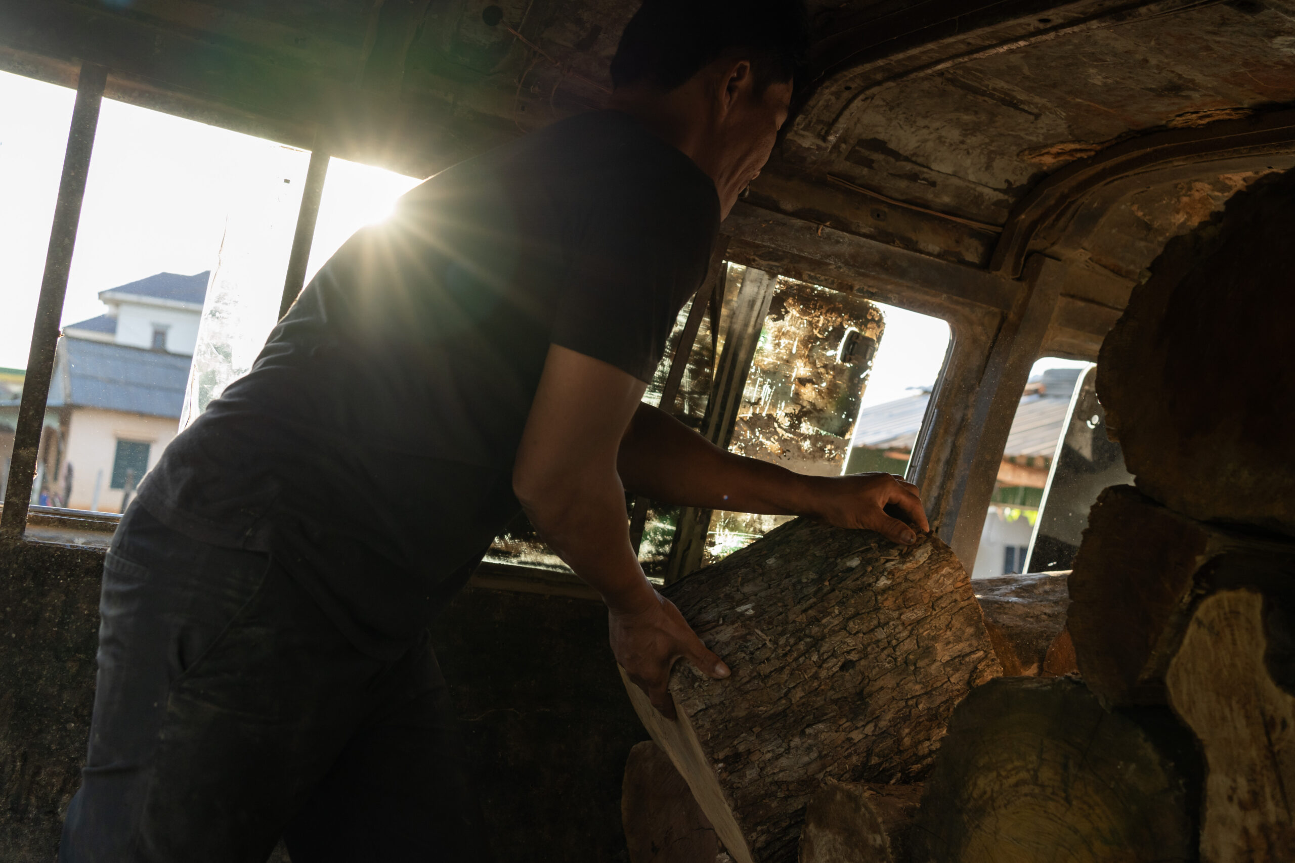 A middleman unloads logs from the Cardamoms that will be sold to garment factories in Kampong Speu and Phnom Penh. Credit: Andy Ball/Mongabay.