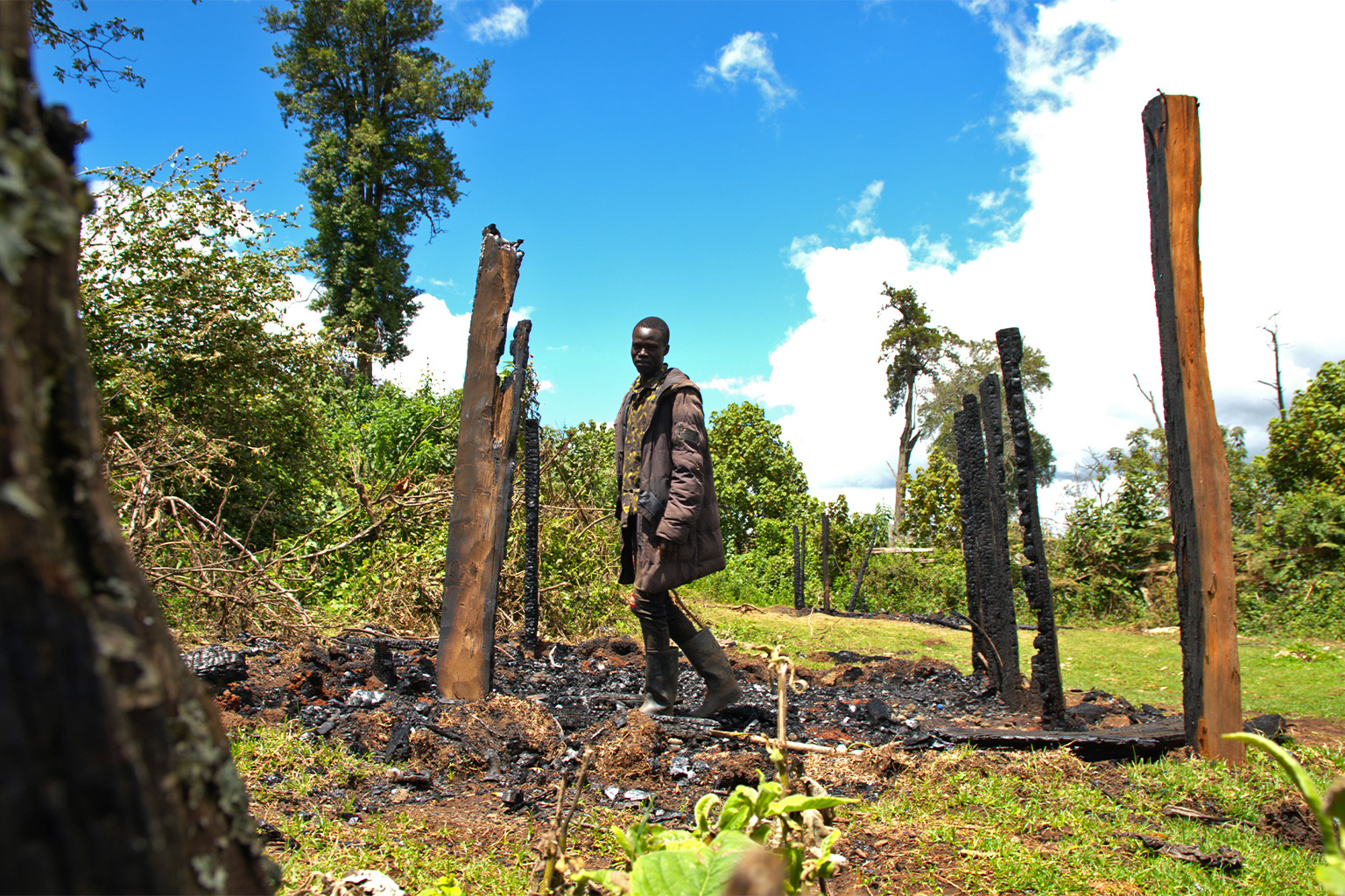 A young man stands where his hut used to be in Sasimwani