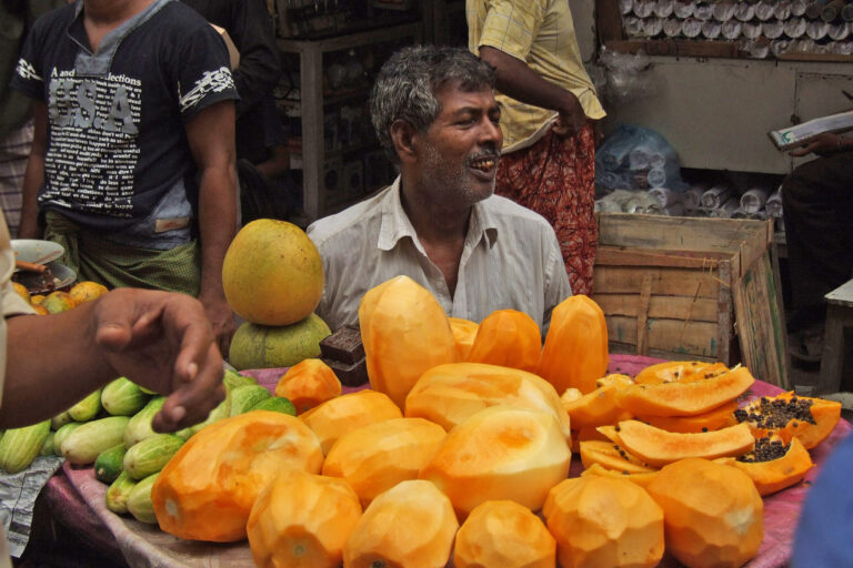 A fruit seller with peeled papaya in a market in Bangladesh.