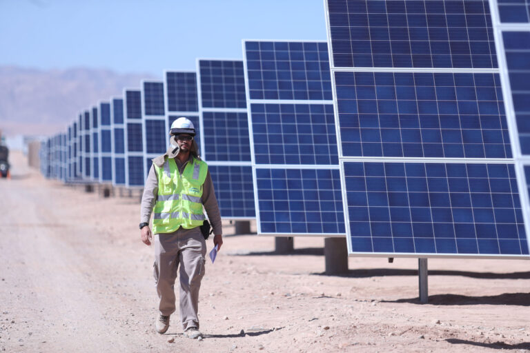 A man walks past solar panels.