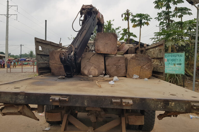 Squared-off blocks of timber, stacked on a flatbed truck fitted with a mechanic loader arm at the Klay Checkpoint, Bomi, Liberia. Image courtesy James Harding Giahyue/The Daylight.