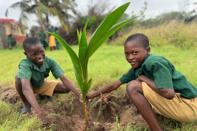 Two school boys planting a tree.